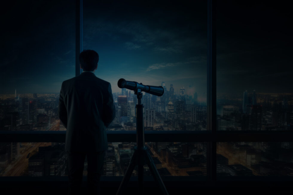 Muž v obleku sám u panoramatického okna s dalekohledem nad večerním městem